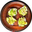 A top-down view of Voro Food's Avocado Toast, featuring four pieces of toast with creamy cheese, sliced avocado, and chili flakes on a rustic plate.