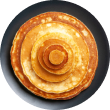 A top-down view of Voro Food's Classic Buttermilk Pancakes, a fluffy stack served with maple syrup on a dark plate.