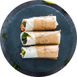 A top-down view of three Mediterranean Veggie Wraps from Voro Food, neatly arranged on a modern dark slate plate.